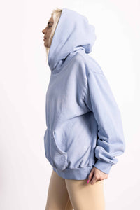 White blond female model with edgy style wearing a heavyweight cotton vintage green hoodie